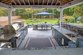 A custom-designed fire pit with seating around it, surrounded by landscaping and greenery, showcasing an outdoor living space created by Mazzucco Construction.